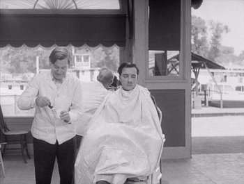 Movie still from “Steamboat Bill, Jr.” (1928), directed by Buster Keaton – An old photo of a man getting his hair cut; Medium shot, Over the shoulder angle