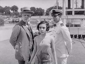 Movie still from “Steamboat Bill, Jr.” (1928), directed by Buster Keaton – An old black and white photo of two men and a woman; Medium shot, High angle