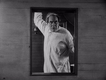 Movie still from “Steamboat Bill, Jr.” (1928), directed by Buster Keaton – A black - and - white photo of a man in a mirror; Medium shot, Low angle