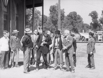 Movie still from “Steamboat Bill, Jr.” (1928), directed by Buster Keaton – A black and white photo of a group of men standing together; Wide shot, Over the shoulder angle