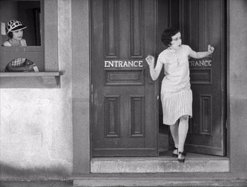 Movie still from “Steamboat Bill, Jr.” (1928), directed by Buster Keaton – A woman standing in front of an entrance door; Wide shot, High angle