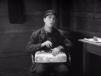 Movie still from “Steamboat Bill, Jr.” (1928), directed by Buster Keaton – A man sitting in a chair holding a piece of paper; Medium shot, High angle