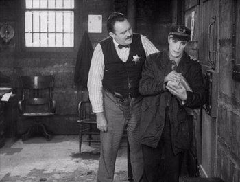 Movie still from “Steamboat Bill, Jr.” (1928), directed by Buster Keaton – Two men standing next to each other in a room; Medium shot, Over the shoulder angle
