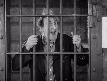 Movie still from “Steamboat Bill, Jr.” (1928), directed by Buster Keaton – An old man is behind bars in a jail cell; Medium shot, High angle