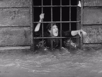 Movie still from “Steamboat Bill, Jr.” (1928), directed by Buster Keaton – A woman is in the water in a jail cell; Wide shot, High angle