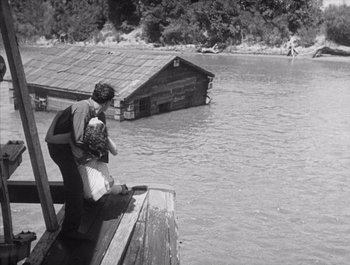 Movie still from “Steamboat Bill, Jr.” (1928), directed by Buster Keaton – A man and a child sitting on a dock; Extreme Wide shot, High angle