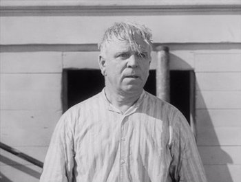 Movie still from “Steamboat Bill, Jr.” (1928), directed by Buster Keaton – An older man standing in front of a building; Close Up shot, Low angle