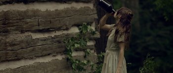 Movie still from “Still” (2018), directed by Takashi Doscher – A woman in a dress drinking from a bottle; Medium shot, High angle