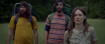 Movie still from “Still” (2018), directed by Takashi Doscher – A group of people with backpacks walking in a field; Medium shot, Over the shoulder angle
