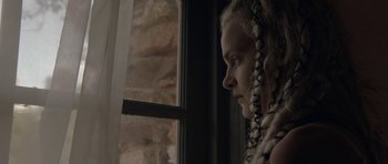 Movie still from “Still” (2018), directed by Takashi Doscher – A woman with braids looking out of a window; Close Up shot, Low angle