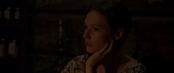 Movie still from “Still” (2018), directed by Takashi Doscher – A woman sitting in the dark with her hand under her chin; Close Up shot, Over the shoulder angle