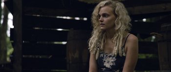 Movie still from “Still” (2018), directed by Takashi Doscher – A woman with long blonde dreadlocks is looking to her left; Close Up shot, Over the shoulder angle