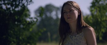 Movie still from “Still” (2018), directed by Takashi Doscher – A woman with long brown hair standing in a field; Close Up shot, Low angle