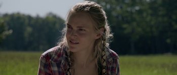 Movie still from “Still” (2018), directed by Takashi Doscher – A young woman with blonde plaited hair wearing a plaid shirt; Close Up shot, Over the shoulder angle