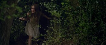 Movie still from “Still” (2018), directed by Takashi Doscher – A young girl is running through the woods; Medium shot, High angle