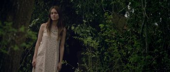 Movie still from “Still” (2018), directed by Takashi Doscher – A young girl standing in front of a bush; Medium shot, Low angle