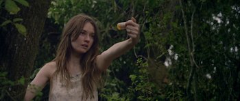 Movie still from “Still” (2018), directed by Takashi Doscher – A woman holding an object in her hand in a forest; Close Up shot, Low angle
