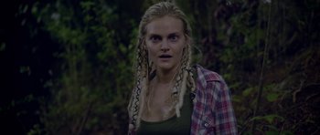 Movie still from “Still” (2018), directed by Takashi Doscher – A woman with dreads standing in the woods; Close Up shot, Over the shoulder angle