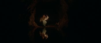 Movie still from “Still” (2018), directed by Takashi Doscher – A person is holding a candle in a cave; Wide shot, Overhead angle