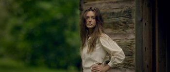 Movie still from “Still” (2018), directed by Takashi Doscher – A woman in a white shirt is posing for a picture; Medium shot, Low angle