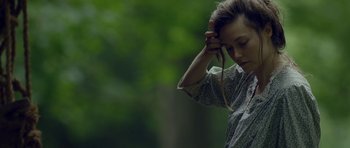 Movie still from “Still” (2018), directed by Takashi Doscher – A young woman holding her head while listening to music on her headphones; Close Up shot, Over the shoulder angle