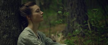 Movie still from “Still” (2018), directed by Takashi Doscher – A woman sitting in the woods with her eyes closed; Close Up shot, Low angle