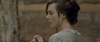 Movie still from “Still” (2018), directed by Takashi Doscher – A young woman with headphones is holding a cell phone; Close Up shot, Over the shoulder angle