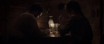 Movie still from “Still” (2018), directed by Takashi Doscher – Two men sitting at a wooden table with a candle; Medium shot, High angle