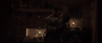 Movie still from “Still” (2018), directed by Takashi Doscher – A man and a woman kissing in a dimly - lit kitchen; Medium shot, High angle