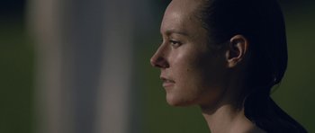 Movie still from “Still” (2018), directed by Takashi Doscher – A woman's face with a green background; Close Up shot, Low angle