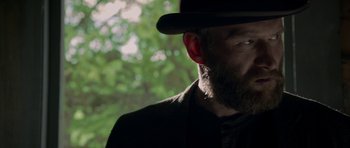 Movie still from “Still” (2018), directed by Takashi Doscher – A man with a beard wearing a black hat; Close Up shot, Low angle
