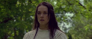 Movie still from “Still” (2018), directed by Takashi Doscher – A woman with long black hair standing in front of a tree; Close Up shot, Low angle