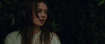 Movie still from “Still” (2018), directed by Takashi Doscher – A woman with long hair is standing in the dark; Close Up shot, Over the shoulder angle