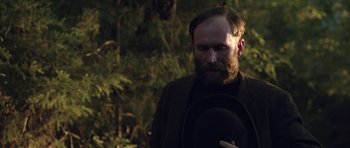 Movie still from “Still” (2018), directed by Takashi Doscher – A man with a beard wearing a black hat; Close Up shot, Over the shoulder angle