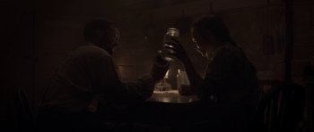 Movie still from “Still” (2018), directed by Takashi Doscher – A man and a woman sitting at a table holding drinks; Medium shot, Low angle