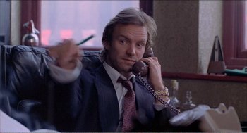 Movie still from “Stormy Monday” (1988), directed by Mike Figgis – A man in a suit holding a phone to his ear; Close Up shot, Low angle