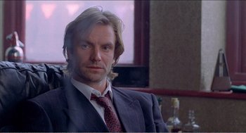 Movie still from “Stormy Monday” (1988), directed by Mike Figgis – A person wearing a suit and tie; Close Up shot, Low angle