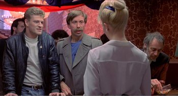 Movie still from “Stormy Monday” (1988), directed by Mike Figgis – A group of people standing next to each other in front of a mirror; Medium shot, Over the shoulder angle