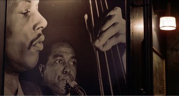 Movie still from “Stormy Monday” (1988), directed by Mike Figgis – A black and white photo of a man playing the saxophone; Extreme Close Up shot, Low angle