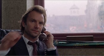 Movie still from “Stormy Monday” (1988), directed by Mike Figgis – A man talking on a phone in front of a window; Close Up shot, Low angle