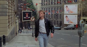 Movie still from “Stormy Monday” (1988), directed by Mike Figgis – A man walking down the street wearing a leather jacket; Wide shot, Low angle