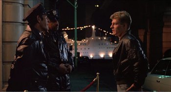 Movie still from “Stormy Monday” (1988), directed by Mike Figgis – A group of men standing next to each other on a dock; Medium shot, Over the shoulder angle