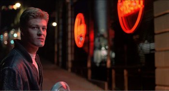 Movie still from “Stormy Monday” (1988), directed by Mike Figgis – A man standing in front of neon lights at night; Close Up shot, Low angle