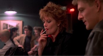 Movie still from “Stormy Monday” (1988), directed by Mike Figgis – A woman smoking a cigarette while sitting in a room; Close Up shot, Low angle