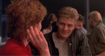 Movie still from “Stormy Monday” (1988), directed by Mike Figgis – A man with blonde spiky hair talking to a woman; Close Up shot, Over the shoulder angle