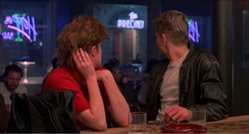 Movie still from “Stormy Monday” (1988), directed by Mike Figgis – Two people sitting at a table in front of each other; Medium shot, Over the shoulder angle