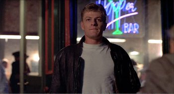 Movie still from “Stormy Monday” (1988), directed by Mike Figgis – A man in a white shirt and a black leather jacket; Medium shot, Low angle