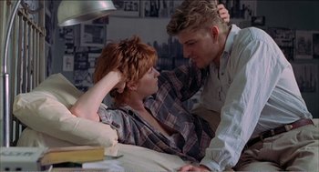 Movie still from “Stormy Monday” (1988), directed by Mike Figgis – A man and a woman are sitting on a bed; Medium shot, Low angle