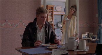 Movie still from “Stormy Monday” (1988), directed by Mike Figgis – A man sitting at a table with a plate of food; Medium shot, Over the shoulder angle