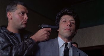 Movie still from “Stormy Monday” (1988), directed by Mike Figgis – A man in a suit and tie holding a gun; Close Up shot, Low angle